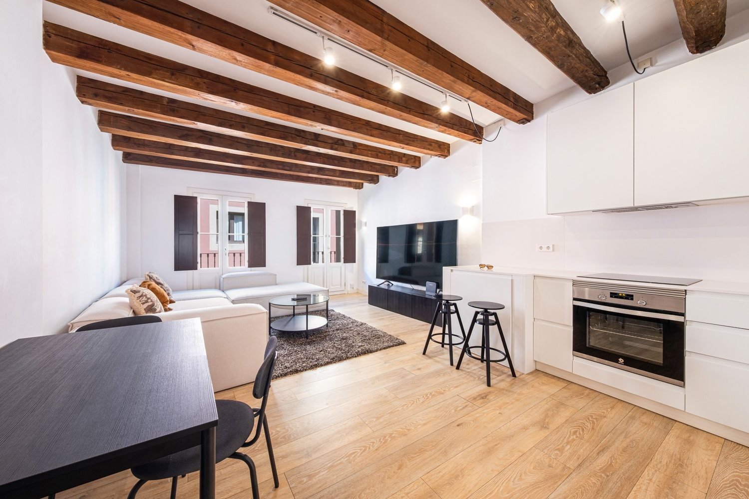 Living and kitchen seen together under the restored beam ceiling