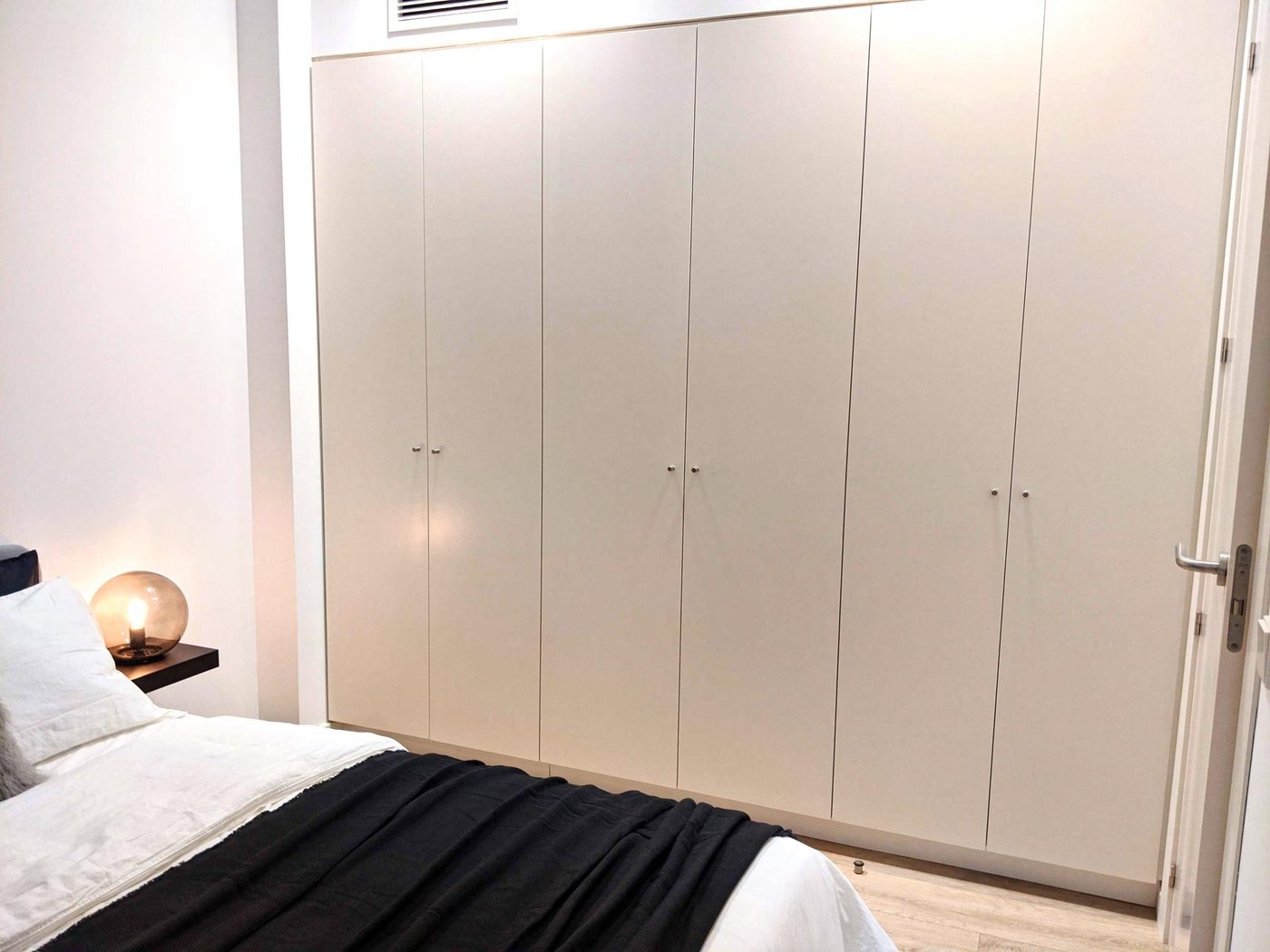 Full-height fitted wardrobes running the length of the bedroom wall