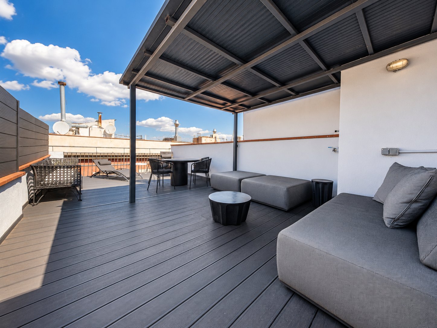 The rooftop terrace under its pergola — lounge seating, dining table and sun lounger on the private deck